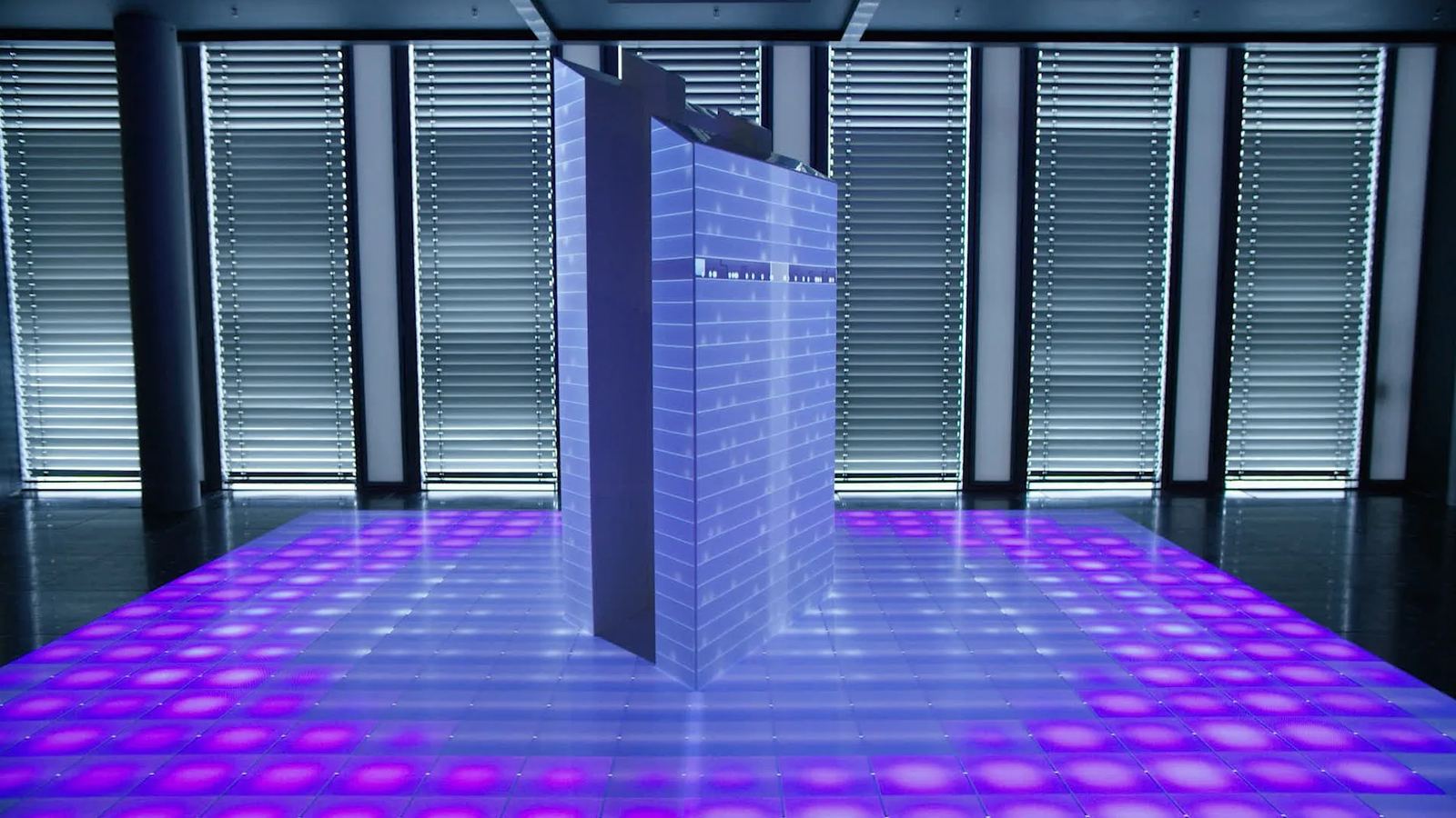 A projection-mapped building model shows live sensor data above an illuminated floor